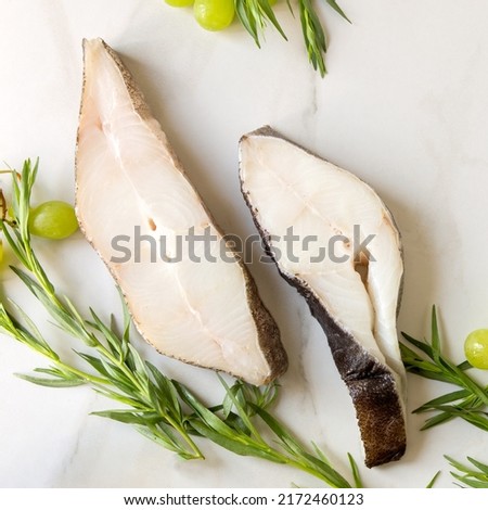 raw halibut steaks, tarragon and grapes on a light marble table