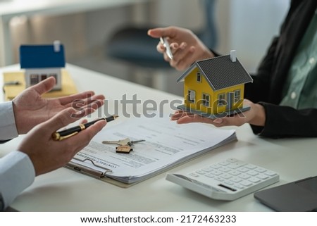 The real estate agent discusses the terms of the home purchase contract and asks the client to sign the documents to legally enter the contract. Ideas for selling a house at an office desk