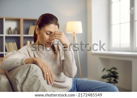 Stressed young Caucasian woman massage eyes suffer from headache or migraine at home. Unhealthy girl struggle with dizziness or blurry vision, relieve tension. Medicine and healthcare concept. Royalty-Free Stock Photo #2172485549