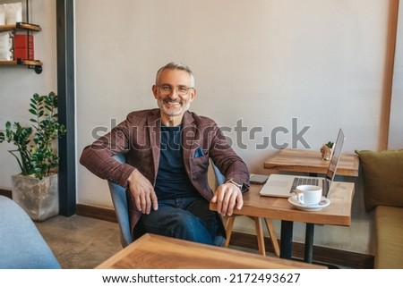 Man sitting at table smiling at camera Royalty-Free Stock Photo #2172493627