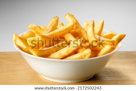Salted French fries in white bowl on a wooden tray Royalty-Free Stock Photo #2172502243