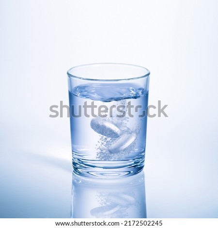  2 effervescent tablets in a glass of water with bubbles
