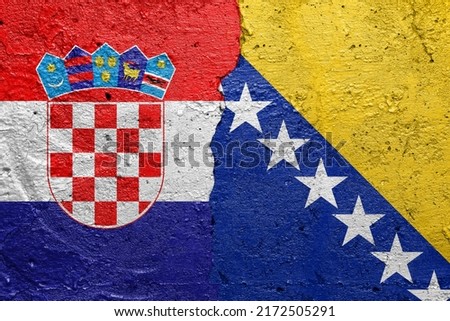 Croatia and Bosnia and Herzegovina - Cracked concrete wall painted with a Croatian flag on the left and a Bosnian flag on the right Royalty-Free Stock Photo #2172505291