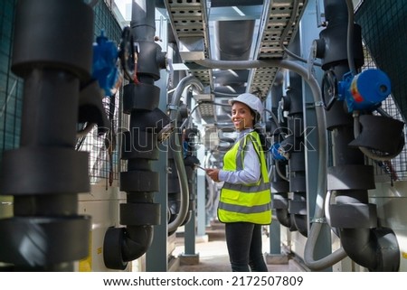 Wide shot of professional engineer or technician worker woman with holding tablet stay and work in area of pipe network of construction site and she also look at camera. Royalty-Free Stock Photo #2172507809