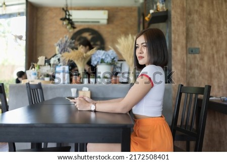A smart woman model short hair in white shirt and orange shorts, she acting for take a picture in cafe and indoor ,outdoor studio