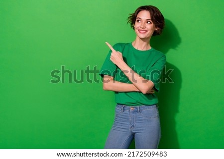 Photo of sweet funny woman dressed summer t-shirt looking pointing empty space isolated green color background