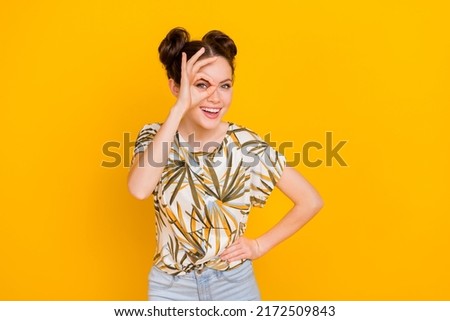 Photo of funky sweet lady dressed print t-shirt looking through okey sign isolated yellow color background