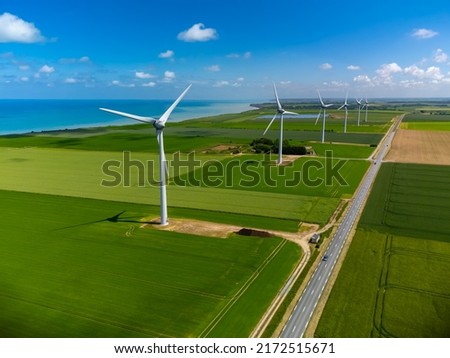 Aerial view on modern wind mills, green grain fields and blue Atlantic ocean in agricultural region Pays de Caux in Normandy, France in summer Royalty-Free Stock Photo #2172515671