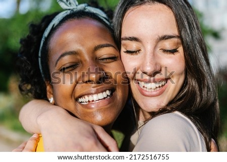 Candid happy multiracial best women friends embracing outdoors - Close up view of two diverse girls hugging each other with closed eyes smiling - Female friendship Royalty-Free Stock Photo #2172516755