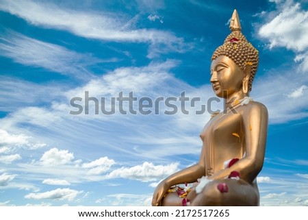 Full body old Buddha statue with raw of Brass. Two Hand of buddha statue with stamp on chest with the fresh sky background. Believe, Culture, Traditional. Concept of Buddhist believe and merit. Royalty-Free Stock Photo #2172517265