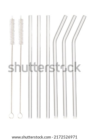 Close up shot of pack of six glass reusable straws. There are three straight straws and three curved straws, two cleaning brushes are isolated on white background. Front view. Royalty-Free Stock Photo #2172526971