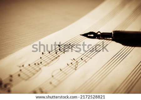 Sheet music on a sheet music stand with an ink pen in the background, macro notes, selective focus Royalty-Free Stock Photo #2172528821