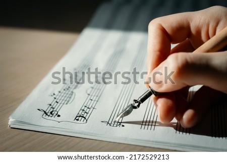 Recording of notes with an ink pen, notes on a sheet music macro, violin and bass keys close-up, selective focus