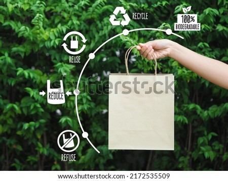 Woman hand holding brown paper bag on green background. Eco bags. Plastic free. Eco friendly concept.