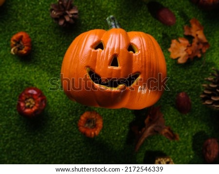 Cheerful orange smiling pumpkin surrounded by small pumpkins on green grass. Background - Halloween. Congratulation, invitation, banner, advertisement, postcard.