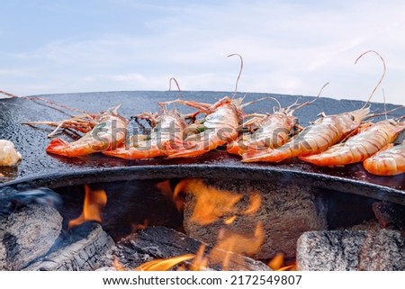 Grilled cooked shrimp with smoke and flames grill. Grilled sea food outdoor summer family party picnic in the park blue sky background. Korean food concept.