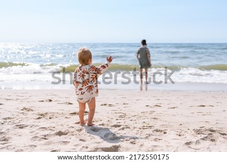 toddler calling his mother at the beach. Conceptual photo of mother-child relationship, separation anxiety, and attachment theory. Royalty-Free Stock Photo #2172550175