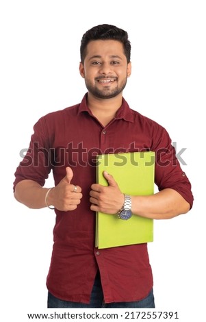 Young happy man holding and posing with the book on white  background.