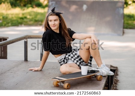Female skater with a skateboard relaxing in the skating rink