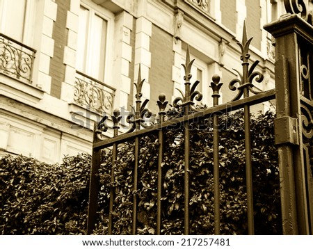 Typical Parisian building with forging gate and colorful firethorn bushes. Autumn in Paris. Aged photo. Sepia.
