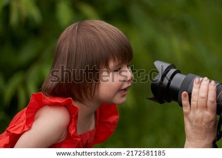A little girl looks curiously into the camera lens in the hands of the photographer.                               