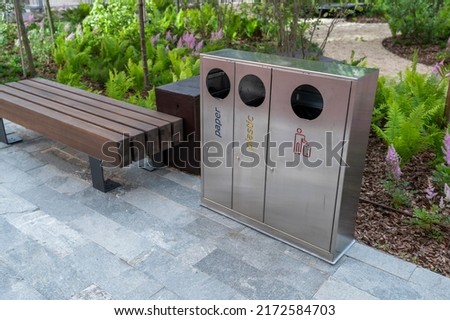 Chrome-plated bins for separate waste near the seat in the park