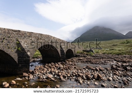 Photo of the Sligachan old bridge in the isle of Skye, Scotland, with the clouds covering a mountain in the background