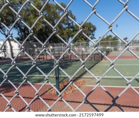 Looking through a chain link fence at an empty tennis court in Los Angeles, CA.