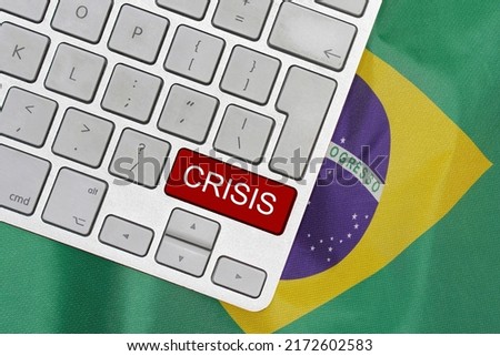 White computer keyboard with red button with word of crisis on Brazil flag background. Global economic, political and financial crisis. Economic crisis and economic recession in Brazil Royalty-Free Stock Photo #2172602583