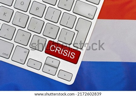 White computer keyboard with red button with word of crisis on Netherlands flag background. Global economic, political and financial crisis. Economic crisis and economic recession in Dutch