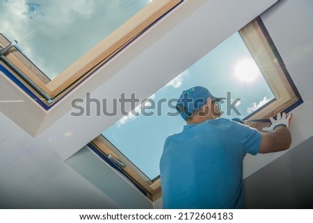 Caucasian Male Worker in Blue Outfit Preparing Skylight Window before Painting the Walls White in the Room. Renovation Work Theme. Royalty-Free Stock Photo #2172604183