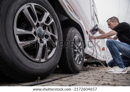 Caucasian Traveler Plugging Cables Into His Recreational Vehicle to Ensure Electricity Power. Camperground Stay During Traveling. Camper Handling Theme. Royalty-Free Stock Photo #2172604657