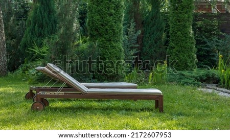 Lounge chairs on the backyard in a beautiful garden. Two empty sunbeds on the grass. Concepts of recreation, tanning in yard. Royalty-Free Stock Photo #2172607953