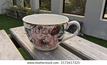 Large high quality ceramic cup with beautiful and colorful floral motifs on a rustic wooden table