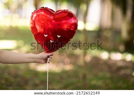 inflatable heart in red color on forest background. Holiday card, concept of happy valentines day love in the air.