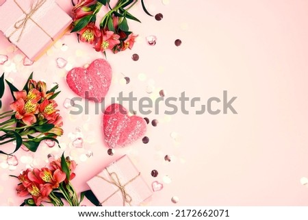 Romantic border of flowers, hearts, gifts and confetti  on pink background. Holiday, birthday, Valentine's day concept. Flat lay, top view, copy space.