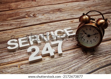 247 Service alphabet letters and alarm clock on wooden background