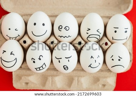 Smiling and sad eggs on a red background
