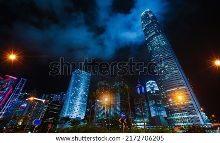 Night city view with skyscrapers under dark cloudy sky, high-rise office buildings of Hong Kong Central District