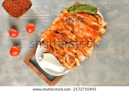 Portion of chicken rotates on the plate served with tomatoes, peppers and yoghurt on wooden table