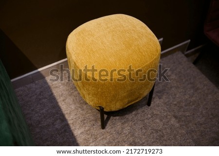Stylish velour yellow footstool, ottoman in the furniture design studio Royalty-Free Stock Photo #2172719273