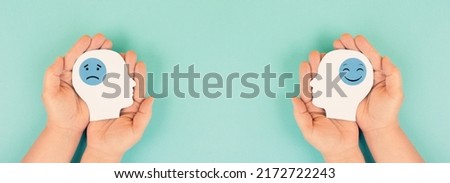 Holding a head with a sad and a happy face in the hands, mental health concept, positive and negative mindset, depression, support and evaluation symbol Royalty-Free Stock Photo #2172722243