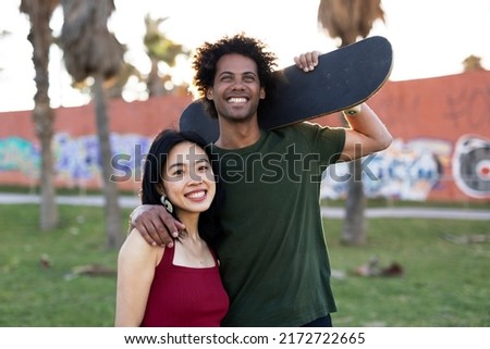 Beautiful couple having fun outdoors. Portrait of an excited young couple with skateboard	