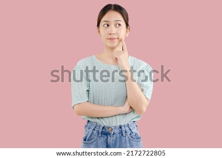Beautiful young Asian girl thinking and looking upwards. The concept of content thinks about future isolated on pink background. Royalty-Free Stock Photo #2172722805