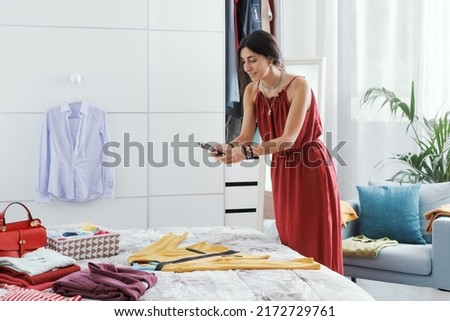 Fashionable woman decluttering her wardrobe, she is selling her used clothes and accessories online