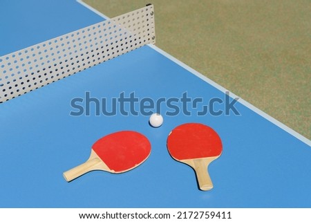 Ping pong tennis table background. Tennis rackets and a ball on a blue sports table.