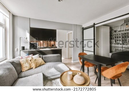 Studio apartment with white walls and open plan kitchen and dining zone with sofa in living room Royalty-Free Stock Photo #2172772805