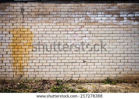 Old weathered wall of bricks with a splash of yellow paint