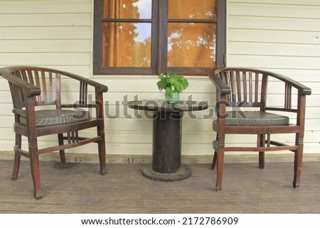 A wooden house in the countryside. View of the front porch, tables and chairs and brown wooden windows Royalty-Free Stock Photo #2172786909