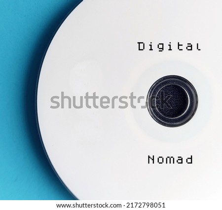 CD on blue background with with job title DIGITAL NOMAD, refers to people who conduct nomadic life by doing remote work from anywhere using digital telecommunications technology Royalty-Free Stock Photo #2172798051